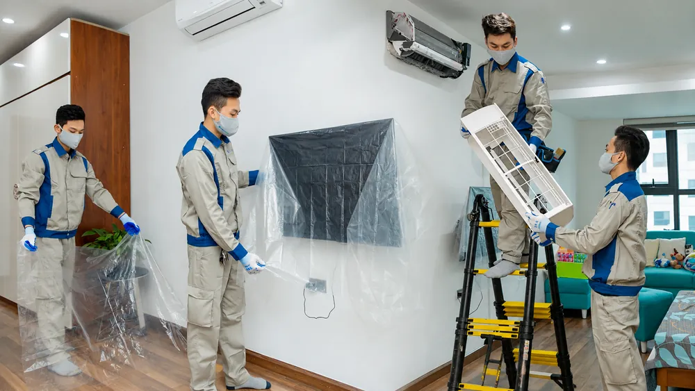 Kỹ thuật viên che chắn đồ đạc và tháo điều hòa tại nhà khách